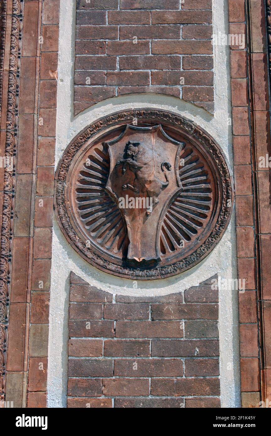 Particolare di una modanatura in terracotta sul lato di uno storico palazzo di Venezia che mostra un toro su uno scudo circondato da raggi di sole. Foto Stock