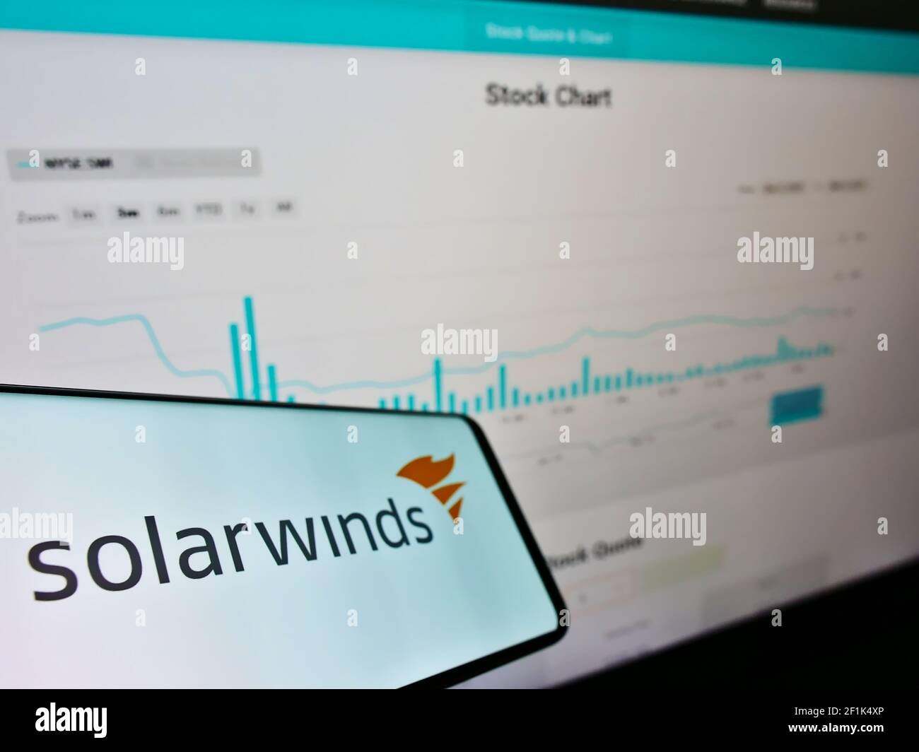 Smartphone con logo della società americana di software SolarWinds sullo schermo di fronte al sito web con tabella di stock. Mettere a fuoco al centro-sinistra del display del telefono. Foto Stock