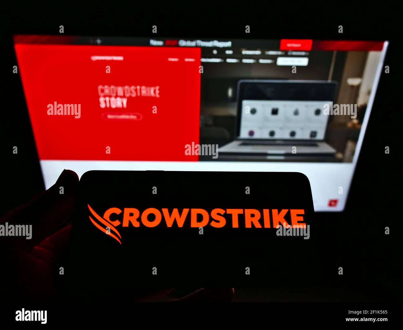 Persona che tiene il cellulare con il logo aziendale della società di software americana CrowdStrike Holdings Inc. Sullo schermo davanti alla pagina web. Mettere a fuoco il display del telefono. Foto Stock