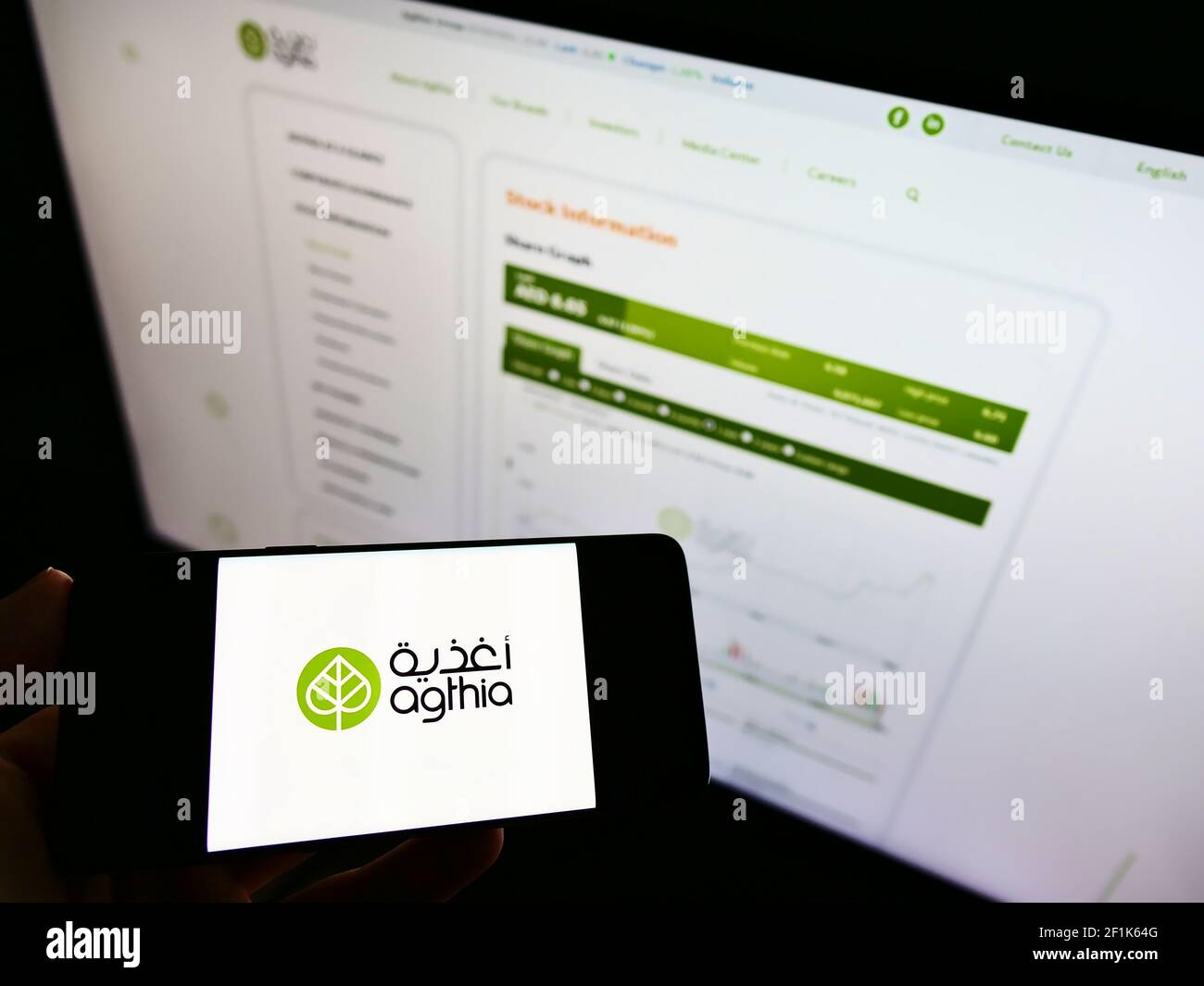 Persona in possesso di smartphone con logo di cibo e bevande Agthia Group PJSC (Abu Dhabi) sullo schermo davanti al sito Web. Mettere a fuoco il display del telefono. Foto Stock