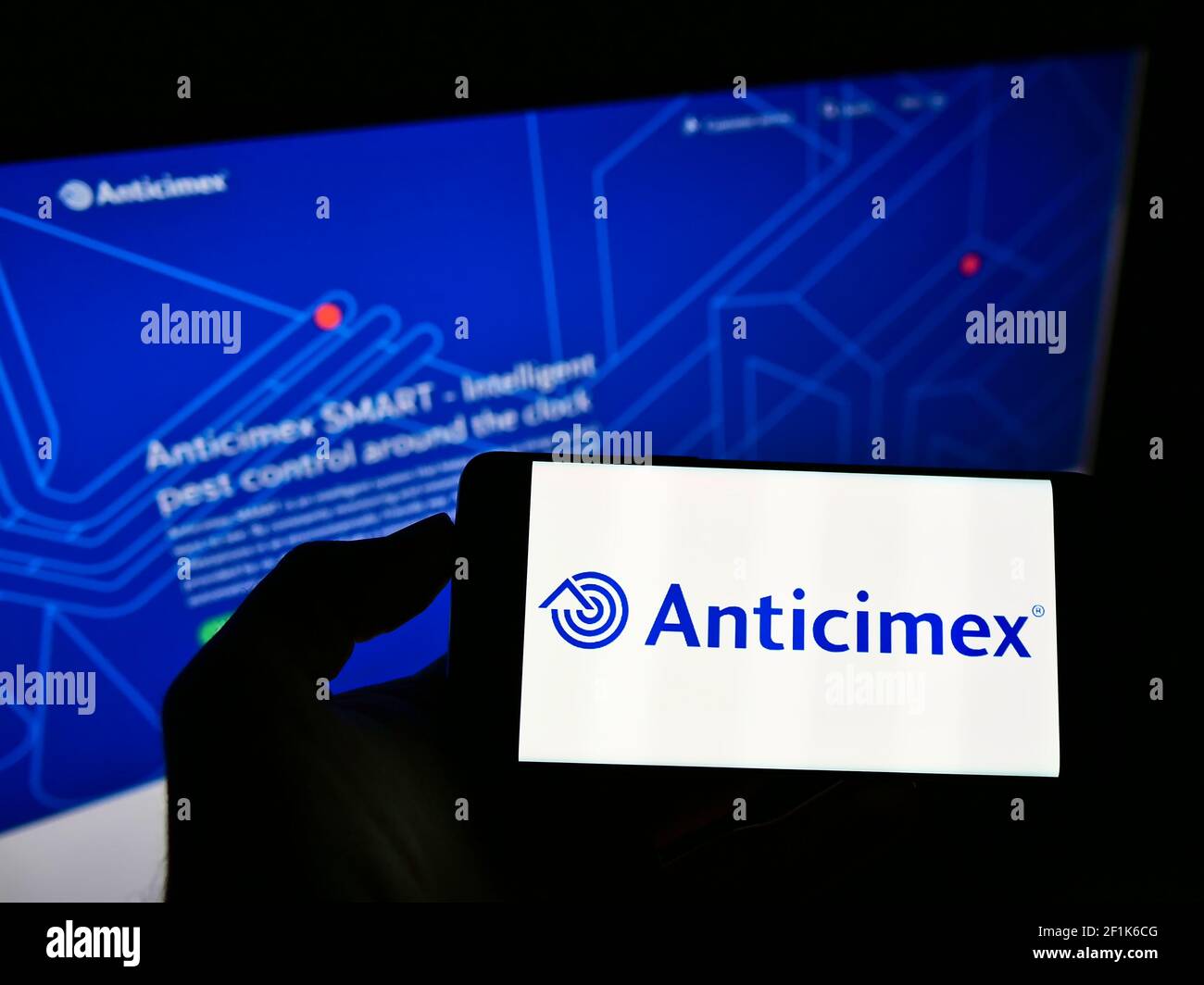 Persona che tiene il cellulare con il logo della società svedese di controllo dei parassiti Anticimex AB sullo schermo di fronte alla pagina web aziendale. Mettere a fuoco il display del telefono. Foto Stock