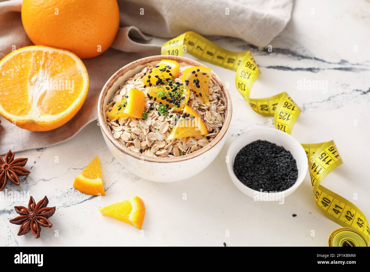 Ciotola con farinata d'avena grezza, arance e semi di chia su sfondo chiaro Foto Stock