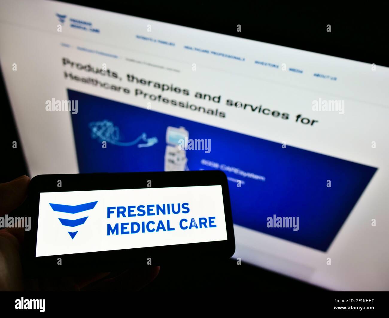 Persona titolare smartphone con logo della società tedesca di dialisi Fresenius Medical Care sullo schermo di fronte al sito web. Mettere a fuoco il display del telefono. Foto Stock