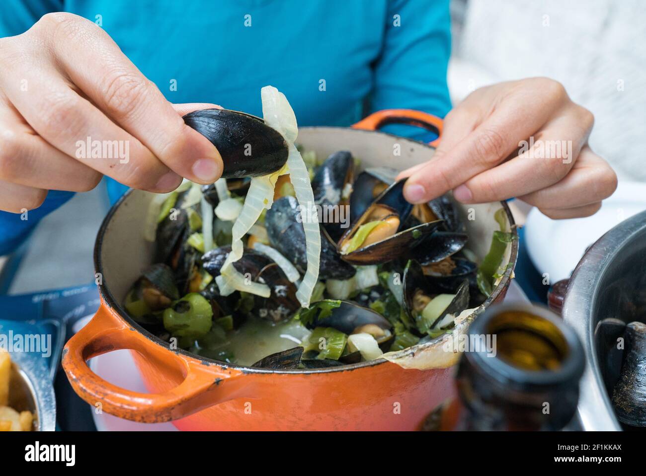 Mani di una donna che mangia mussel tradizionale e patatine fritte Piatto chiamato Moules et Frites Foto Stock
