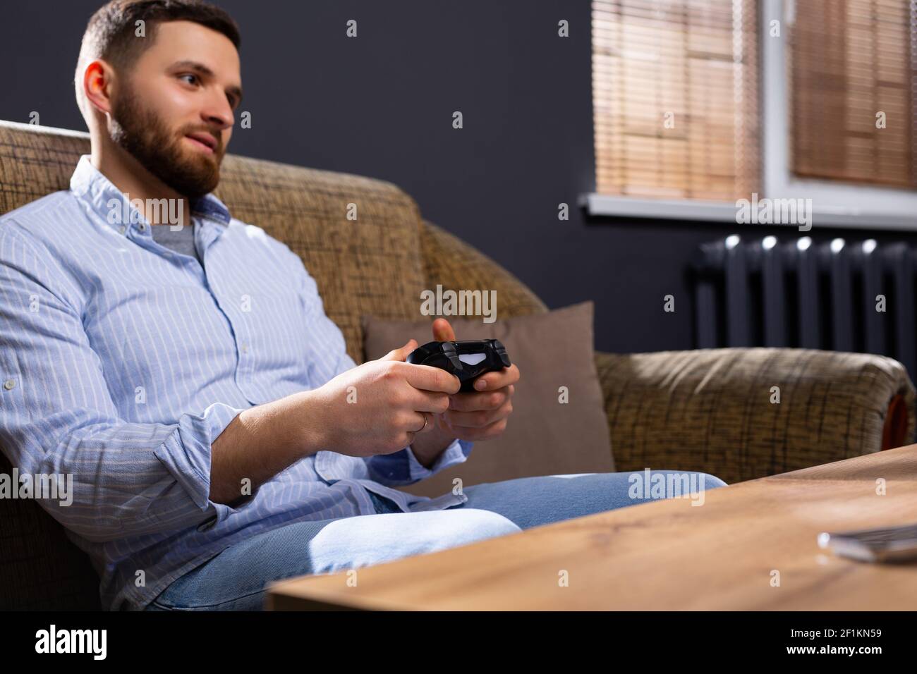 Foto del profilo di un uomo che gioca con la console di gioco joystick e emotivamente gioire, divertente tempo a casa. Tempo libero e stile di vita Foto Stock