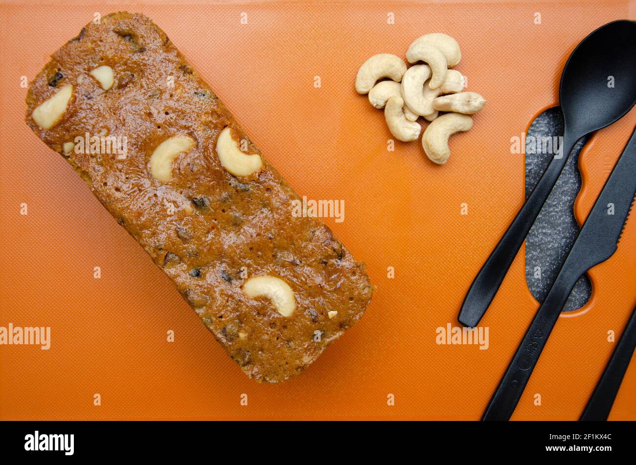 Torta fatta in casa di Rawa e noci di anacardi su tritare di colore arancione scheda Foto Stock