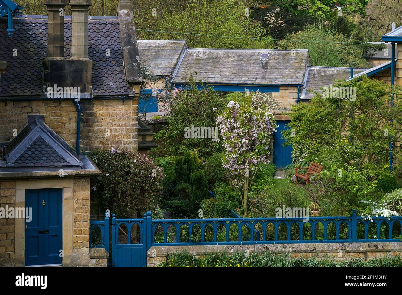 Casa e giardino nel villaggio di Edensor, Derbyshire, UK; con la caratteristica cornice blu della tenuta Chatsworth. Foto Stock