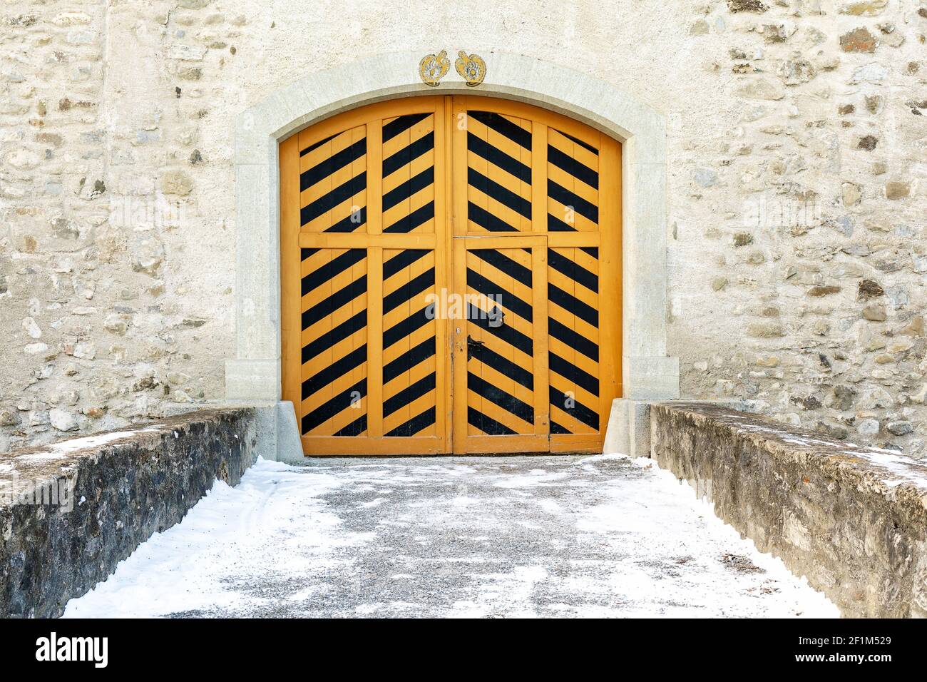Porte in legno a strisce nere e gialle del castello in una giornata invernale innevata. Foto Stock