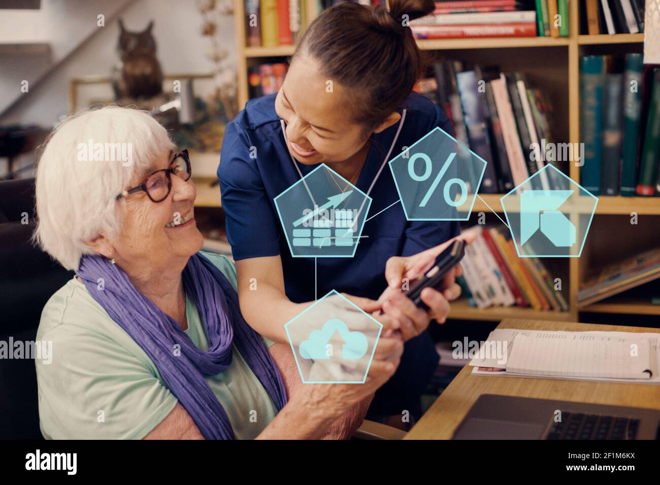 Home carer aiutare donna anziana ad utilizzare il telefono cellulare Foto Stock