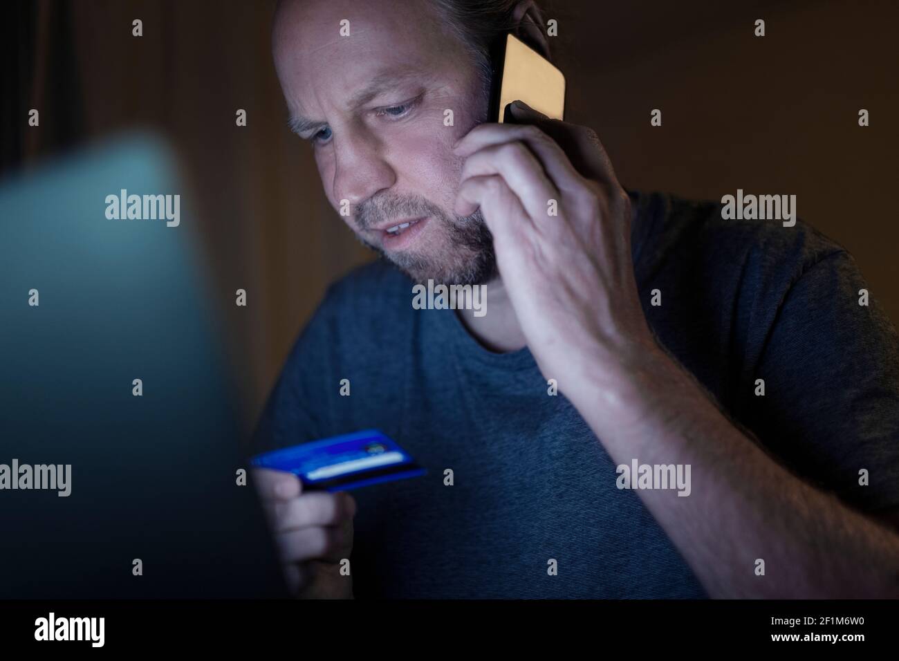 Uomo arrabbiato con carta di credito che prende sul telefono cellulare Foto Stock