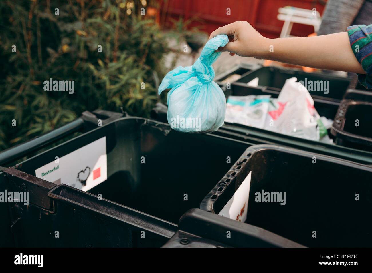 Mani di Mans che mettono il sacchetto di plastica nel contenitore di riciclaggio Foto Stock
