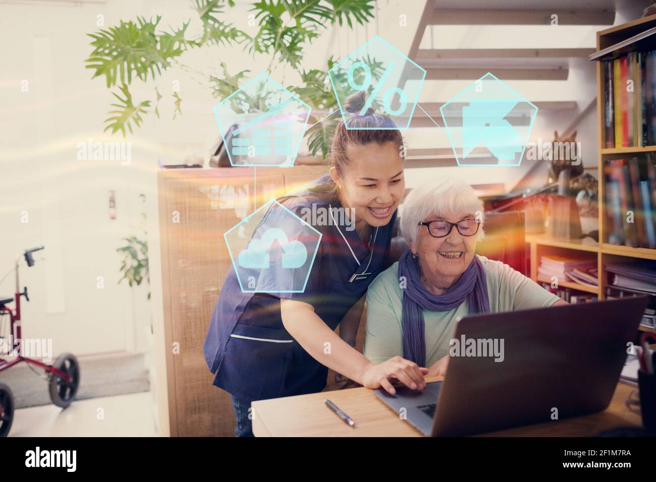 Home carer che aiuta la donna anziana a utilizzare il computer portatile Foto Stock