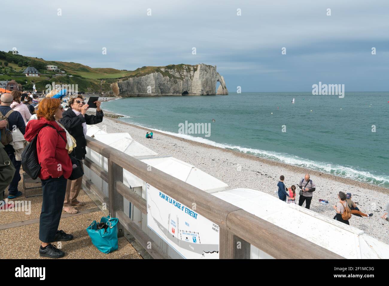 Molti turisti godono di una giornata sulle spiagge rocciose di Etretat sulla costa della Normandia Foto Stock