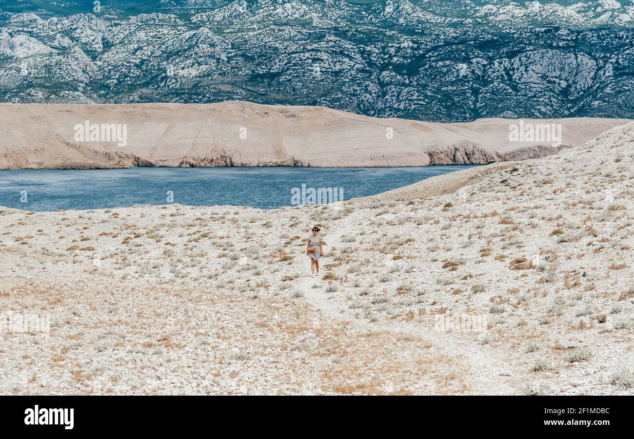 Camminata su un sentiero di ghiaia lungo una costa rocciosa. Isola, mare, escursioni, avventura, ampio spazio, montagne. Isola di Pag, Croazia. Foto Stock