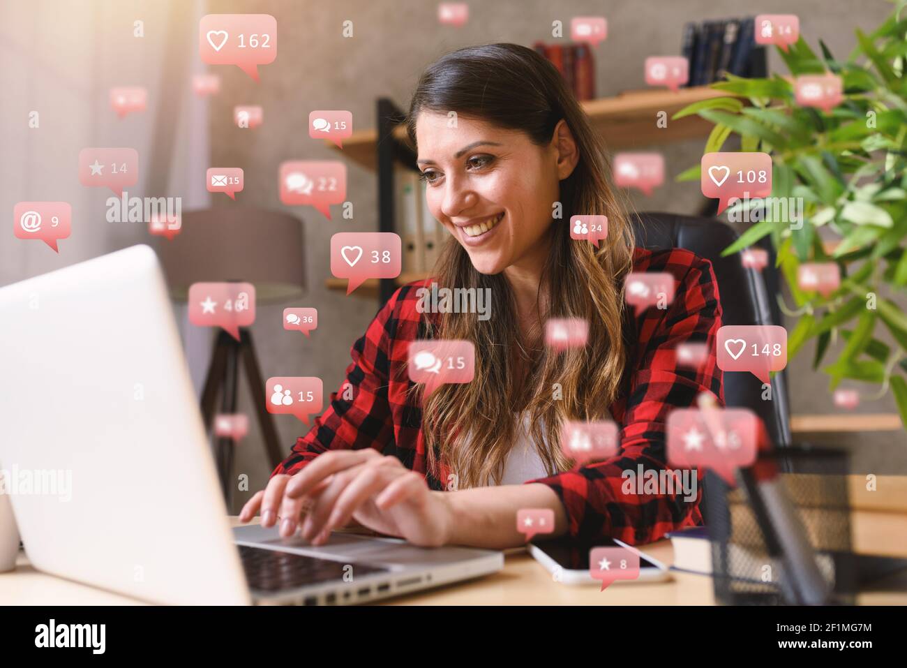 Happy woman chats via laptop con messaggi di social network, chat e icone utente Foto Stock