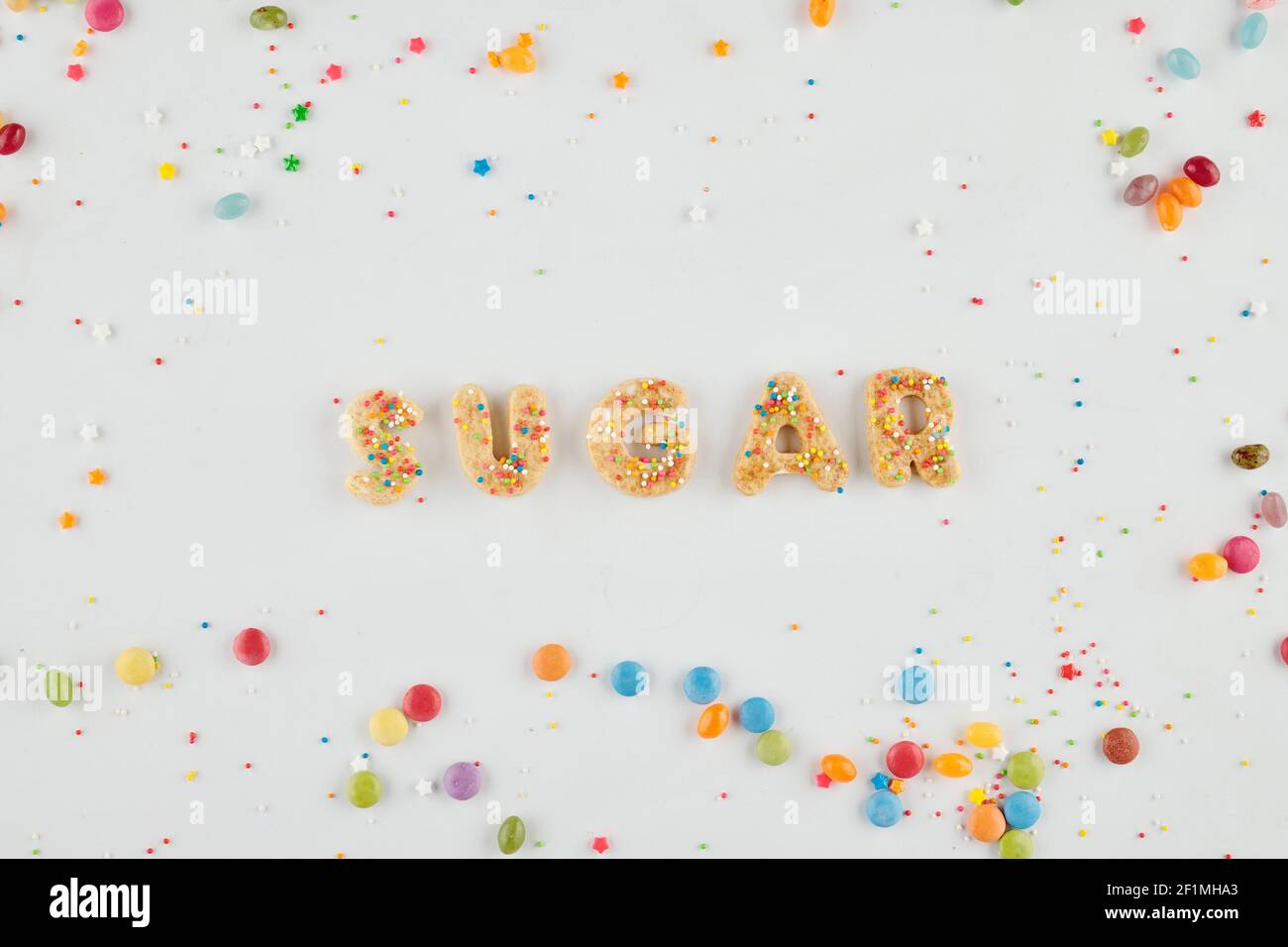 Parola zucchero fatto di lettere biscotto e iridato spruzzare su sfondo bianco, vista dall'alto Foto Stock