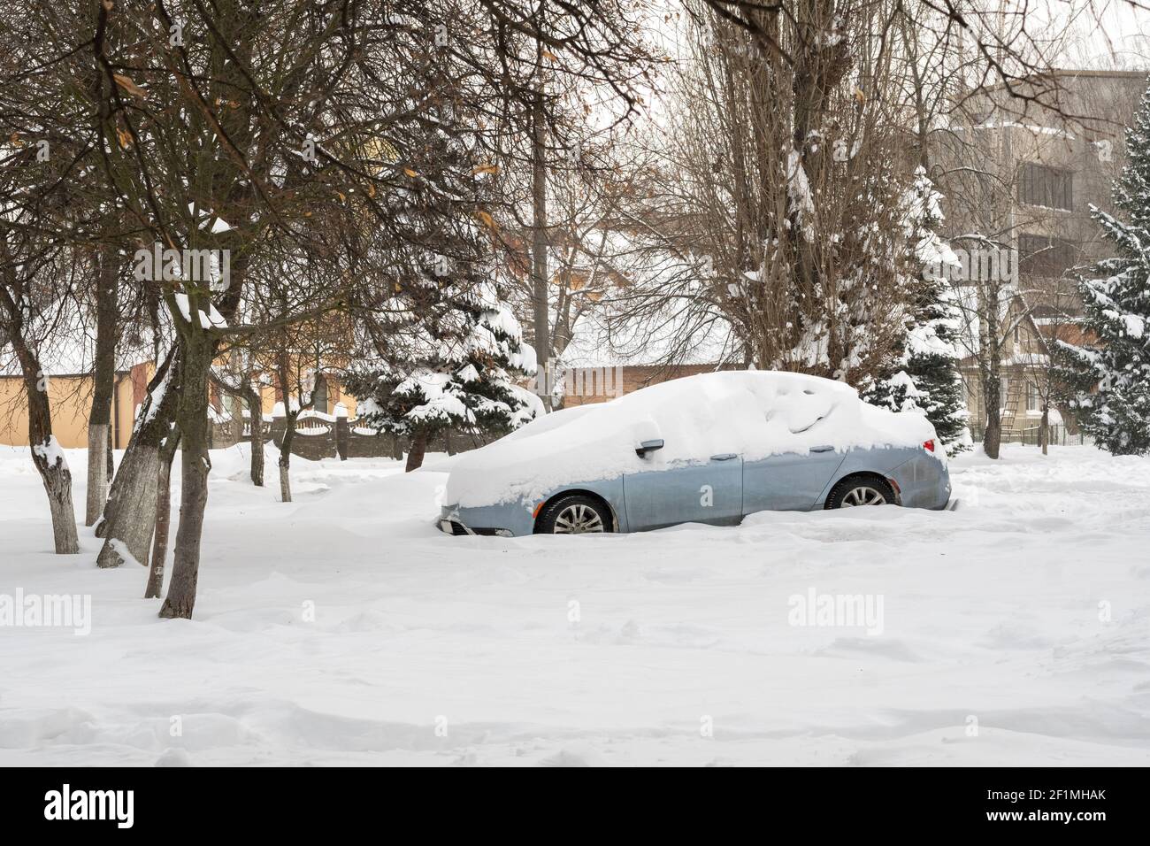 Città strada dopo Blizzard. Automobili bloccate sotto la neve e il ghiaccio. Veicolo sepolto in una deriva da neve sulla strada. Parcheggio in inverno dopo una nevicata pesante Foto Stock