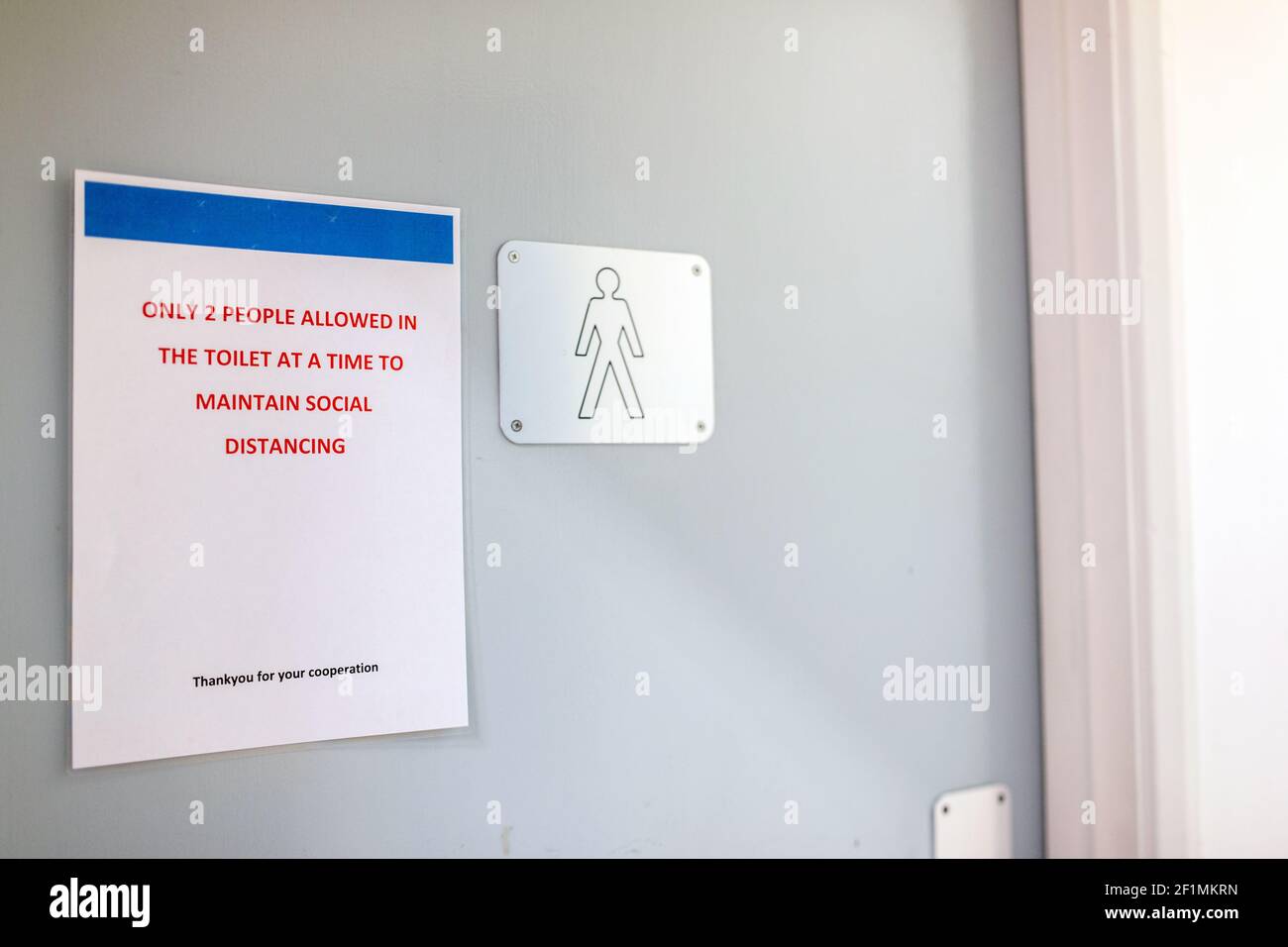 Covid 19 regole sign sulla porta dei bagni maschi in un commercio commerciale. Distanza sociale, sicurezza, nuovo concetto normale, ambiente di lavoro Foto Stock