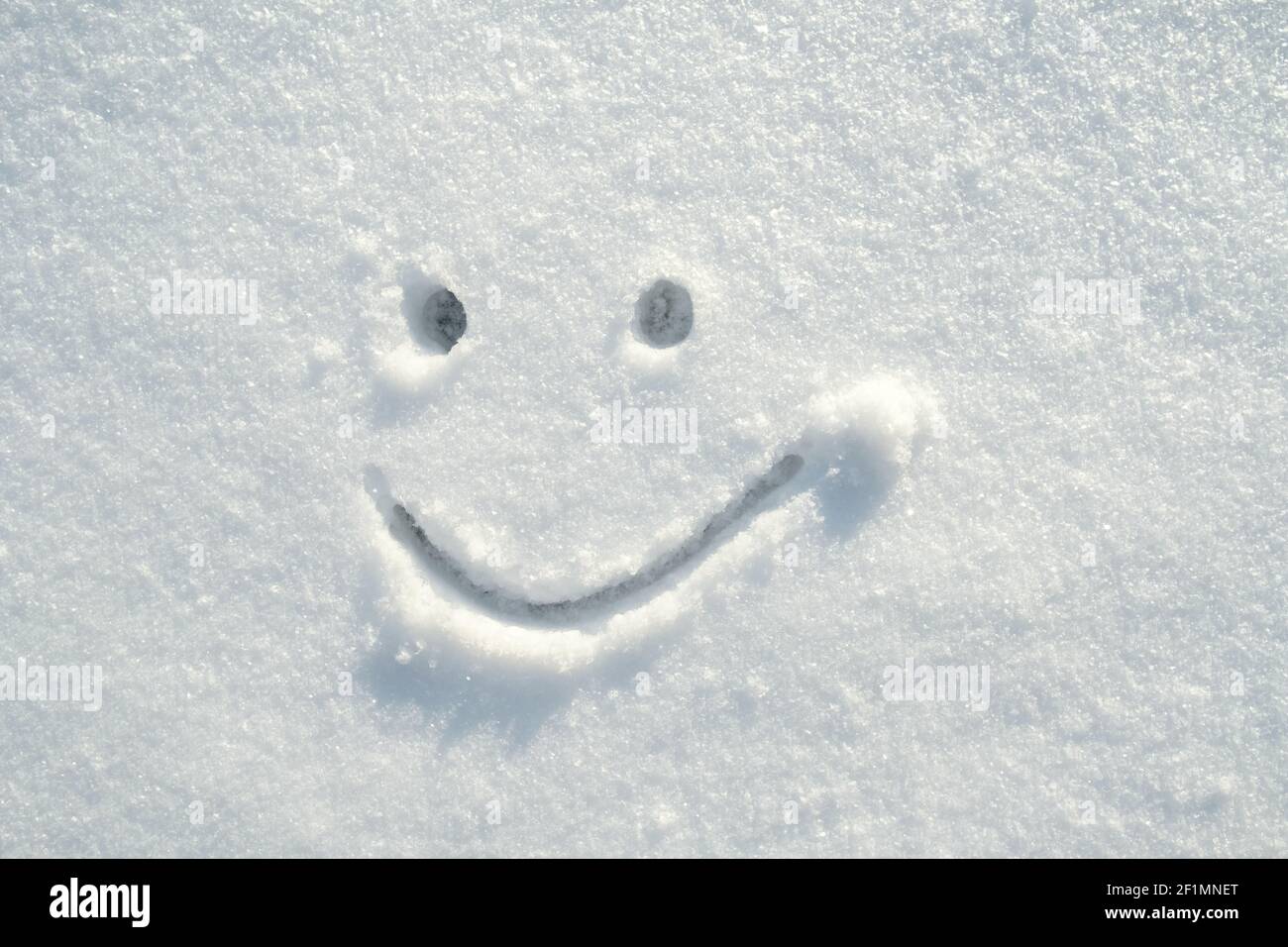 Faccia contenta, faccia sorridente carino disegnata nella neve in una giornata di sole inverno. Spazio di copia. Foto Stock