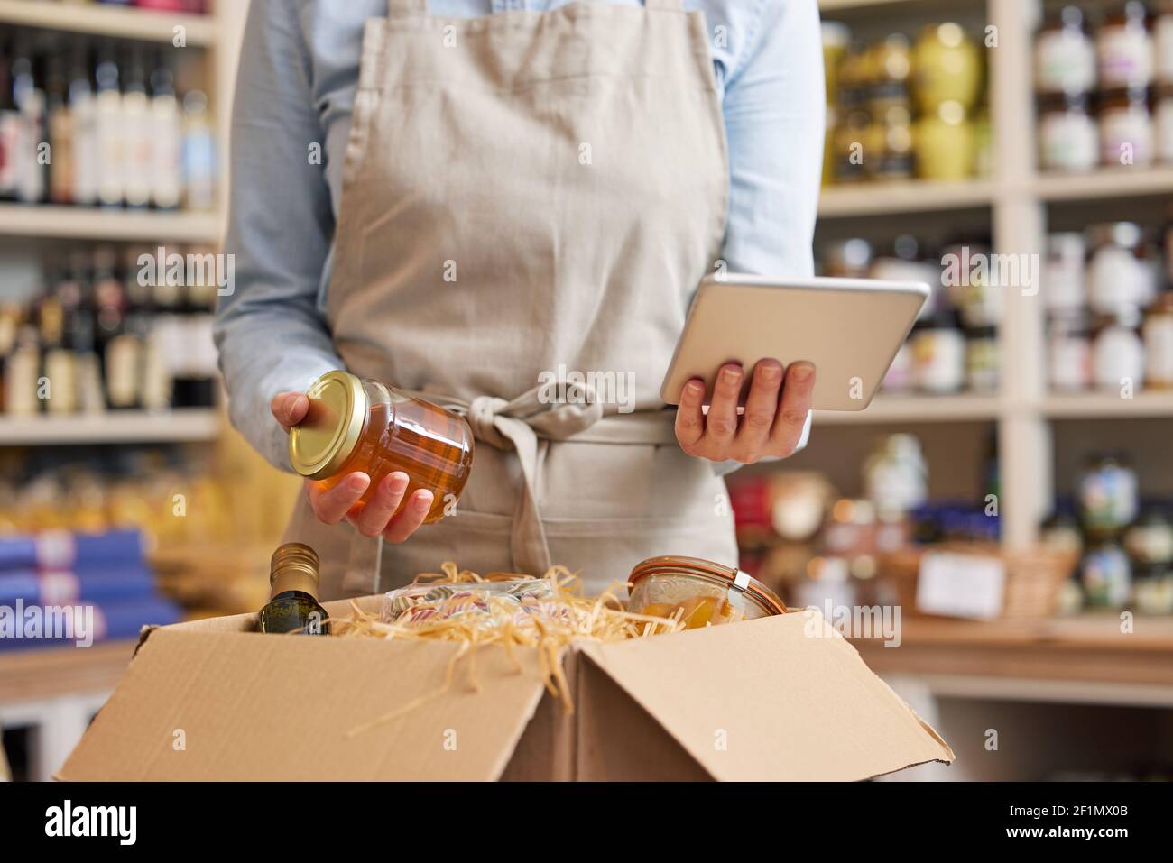 Primo piano del proprietario femminile di Delicatessen Food Shop con Tavoletta digitale preparazione ordine di alimentari online Foto Stock