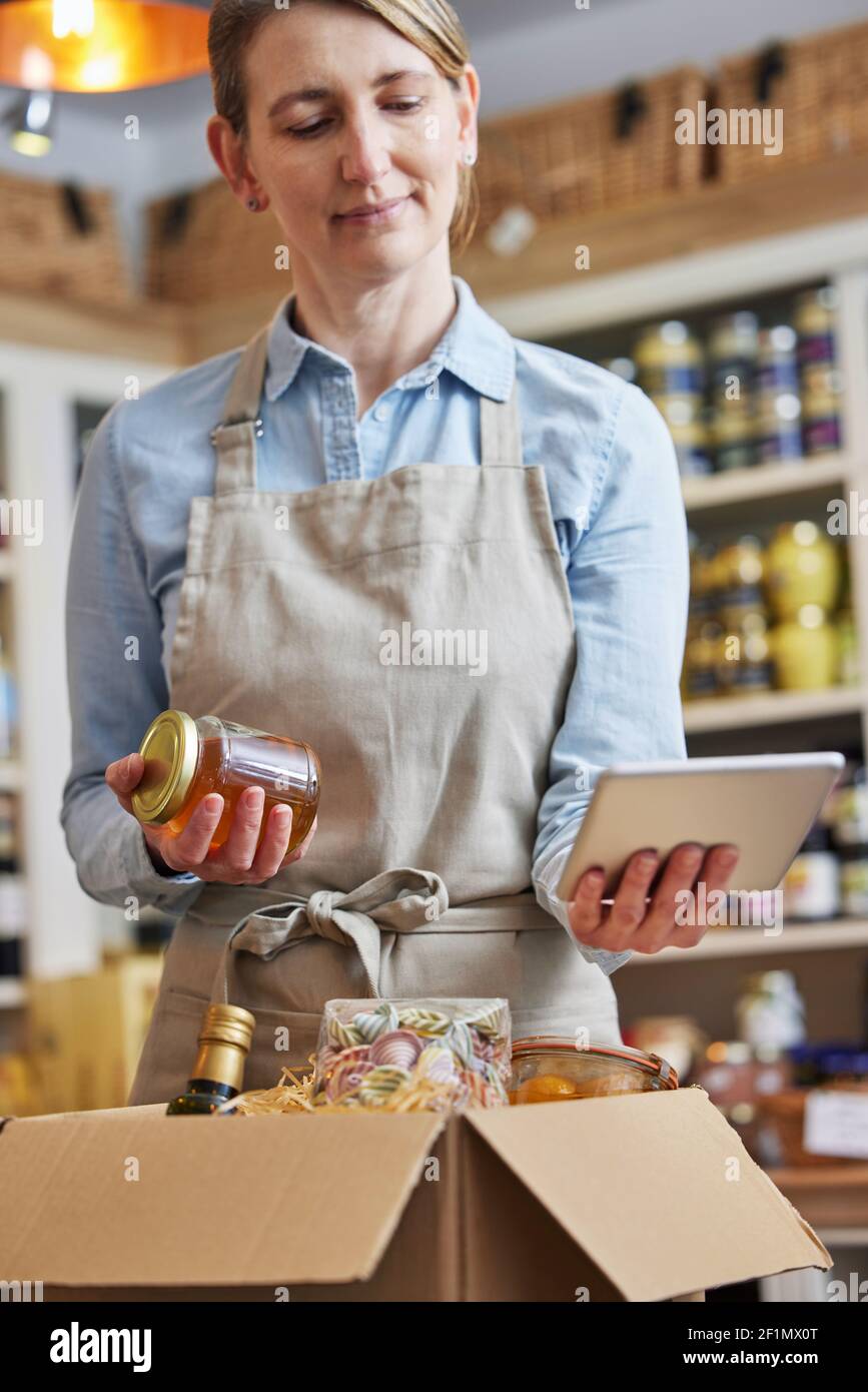 Donna proprietaria di Delicatessen Food Shop con preparazione di tavolette digitali Ordine di alimentari online Foto Stock