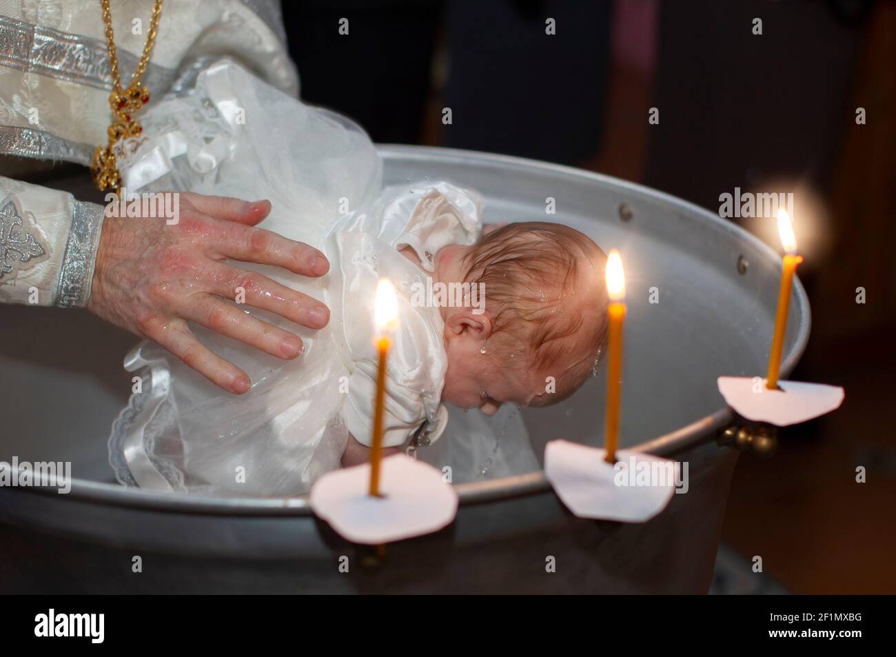 Rito ortodosso del battesimo di un bambino. Le mani del sacerdote bagnano  il bambino nel bagno battesimale Foto stock - Alamy