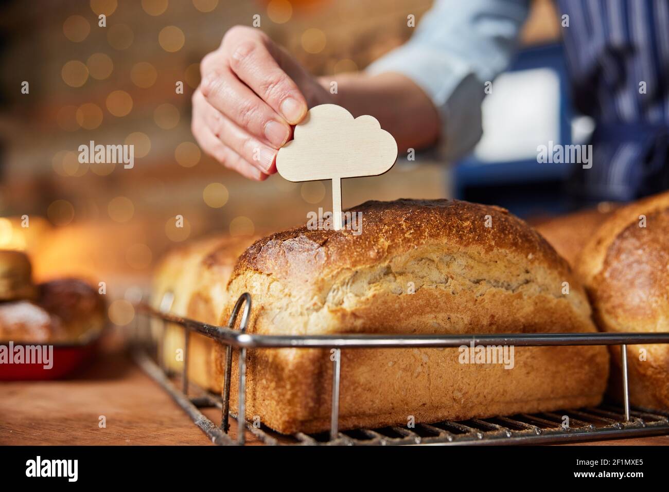 Assistente vendite in panetteria mettendo l'etichetta vuota in appena sfornata Pane di pasta di zucca al forno Foto Stock