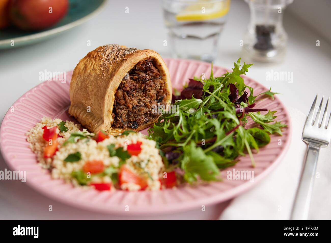 Pasto vegano sul piatto con Roll saporito ripieno di ceci Lenticchie e funghi accanto a couscous e insalata Foto Stock