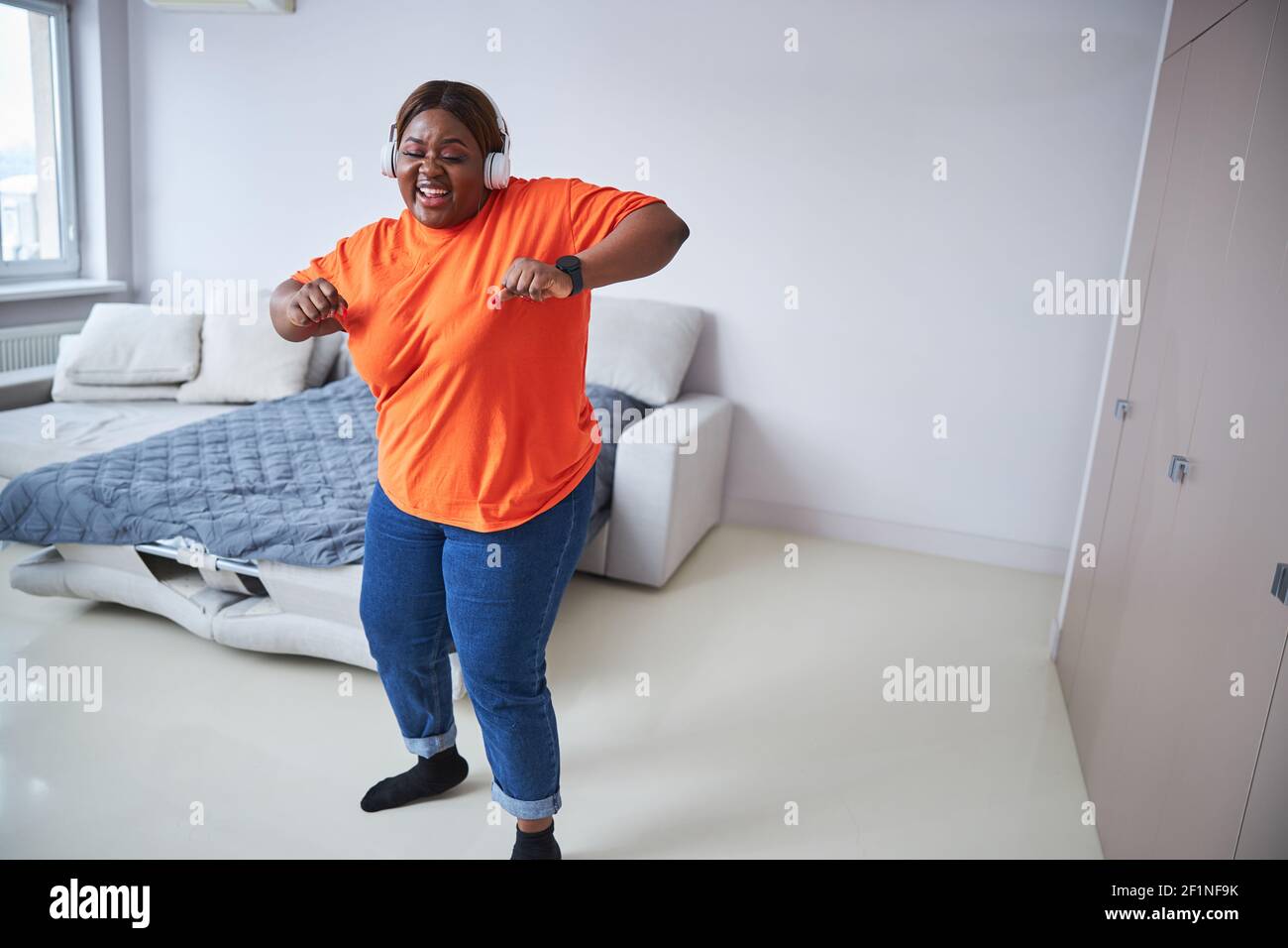 Donna allegra ed eccitata che danzava nel suo soggiorno Foto Stock