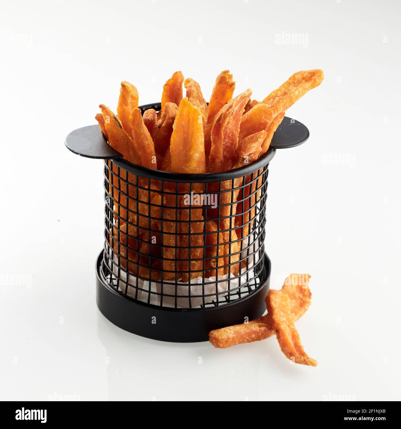 Deliziose patatine fritte croccanti in un secchio di metallo posto su bianco sfondo in studio Foto Stock