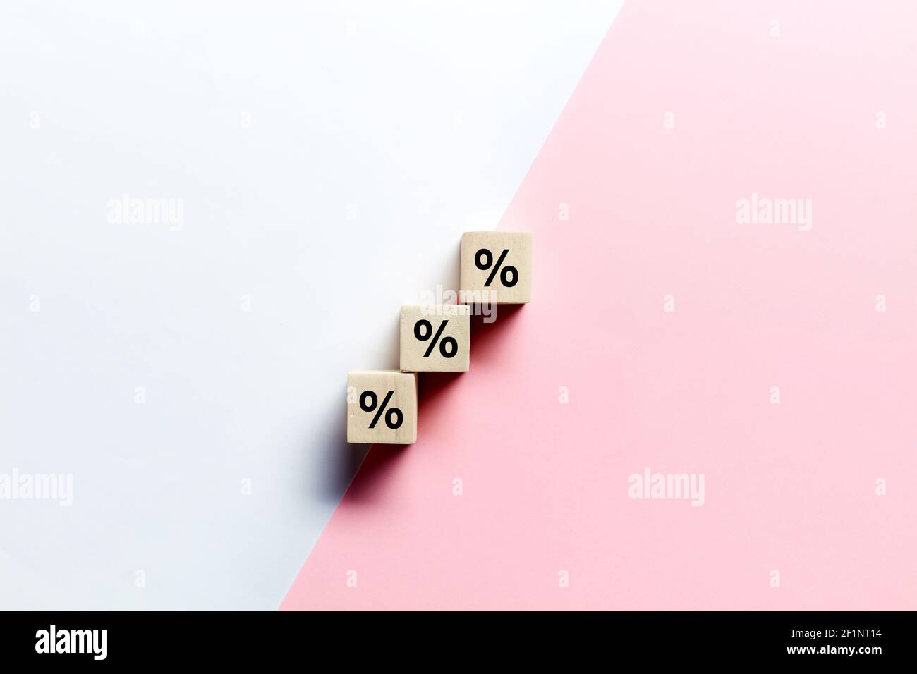 Blocchi di legno impilati come scala con simbolo percentuale o percentuale su sfondo rosa e bianco. Sconto sulle vendite o concetto di tasso d'interesse finanziario Foto Stock