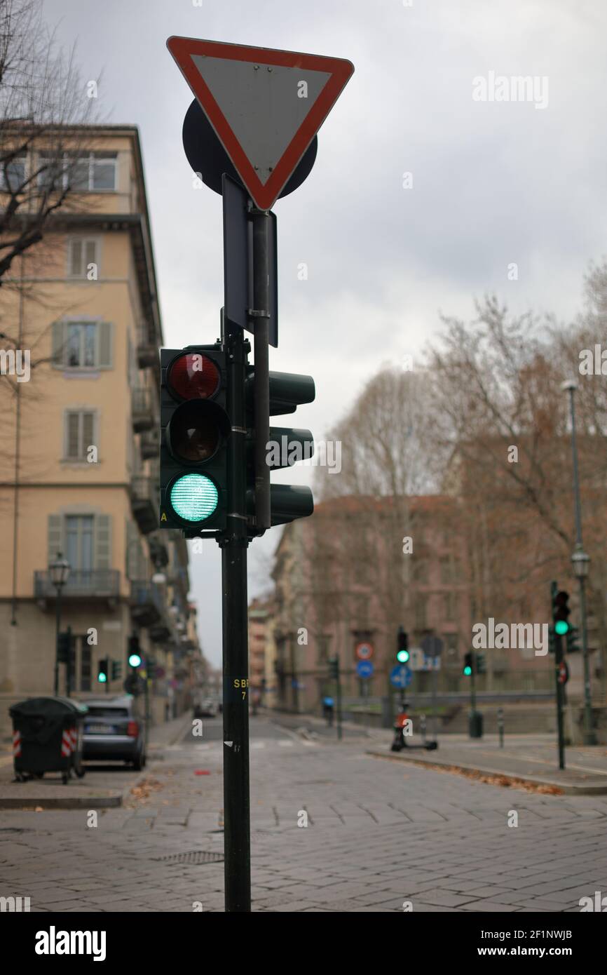 Semafori in verde in corrispondenza di un incrocio su strada una giornata nuvolosa in città con edifici nel sfondo Foto Stock
