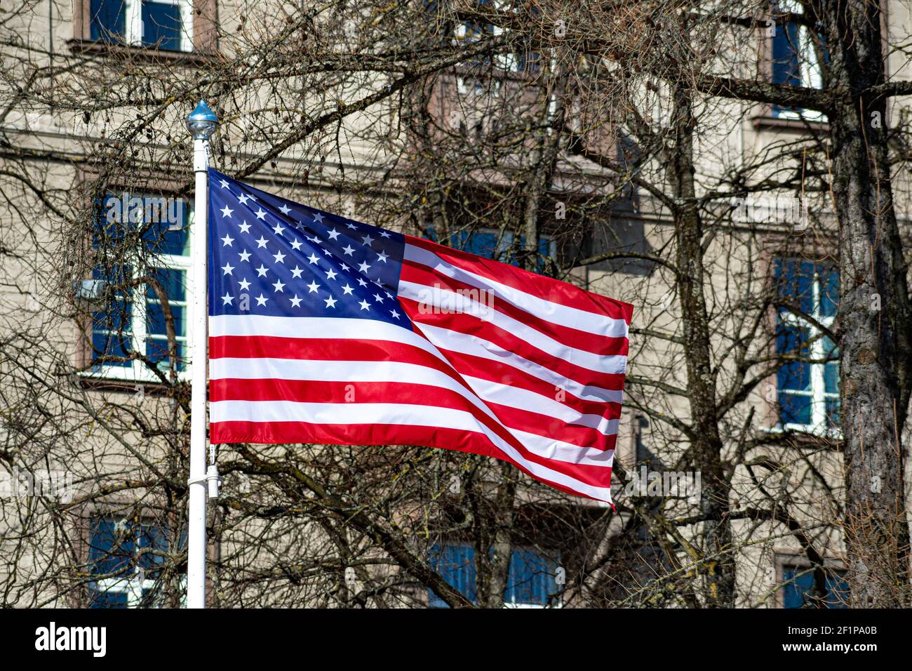 USA, Stati Uniti, bandiera americana sventolando in città con edifici e parco sullo sfondo Foto Stock