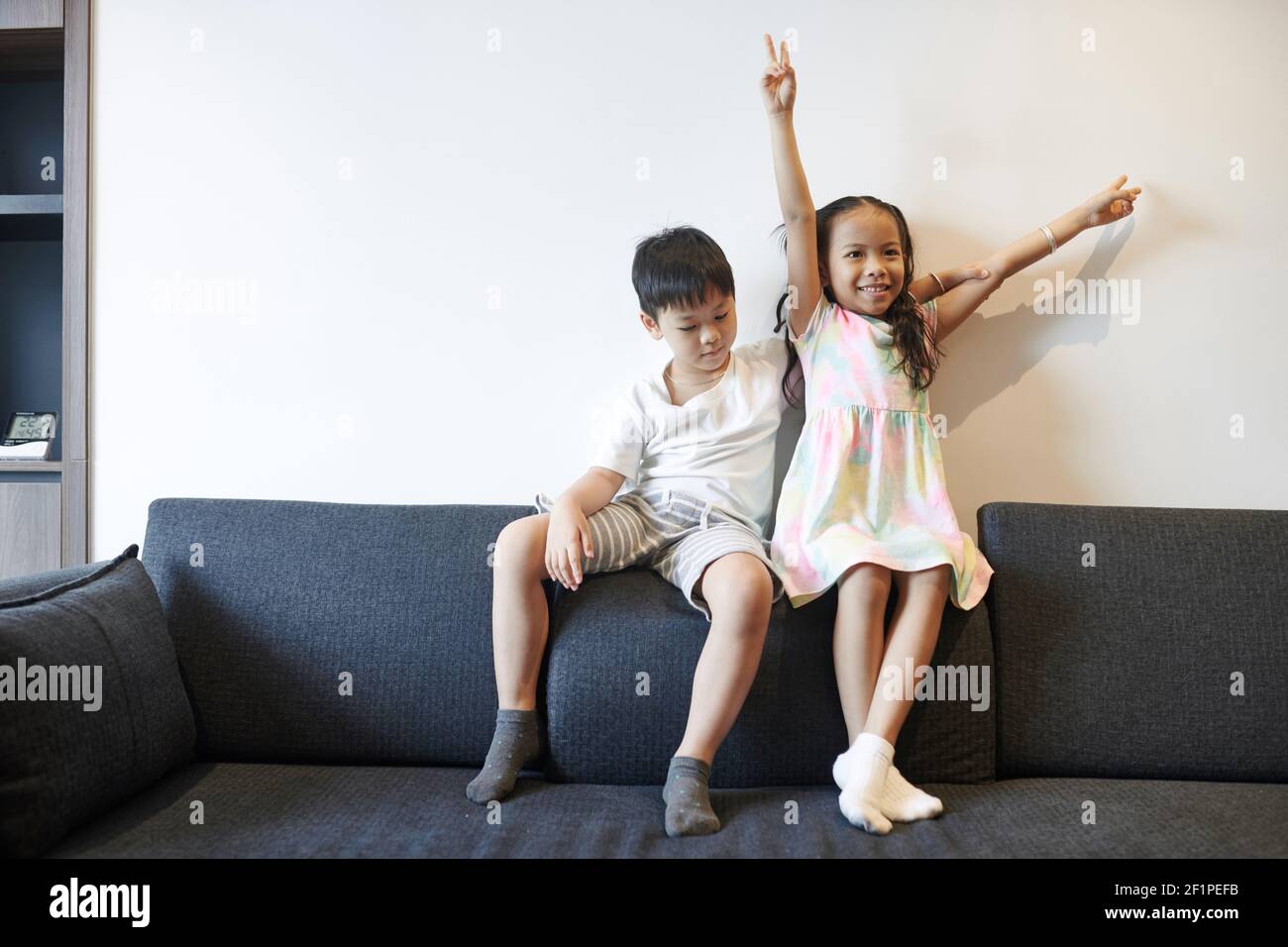 Felice fratello e sorella asiatica presteen che gioca sul divano a. casa Foto Stock