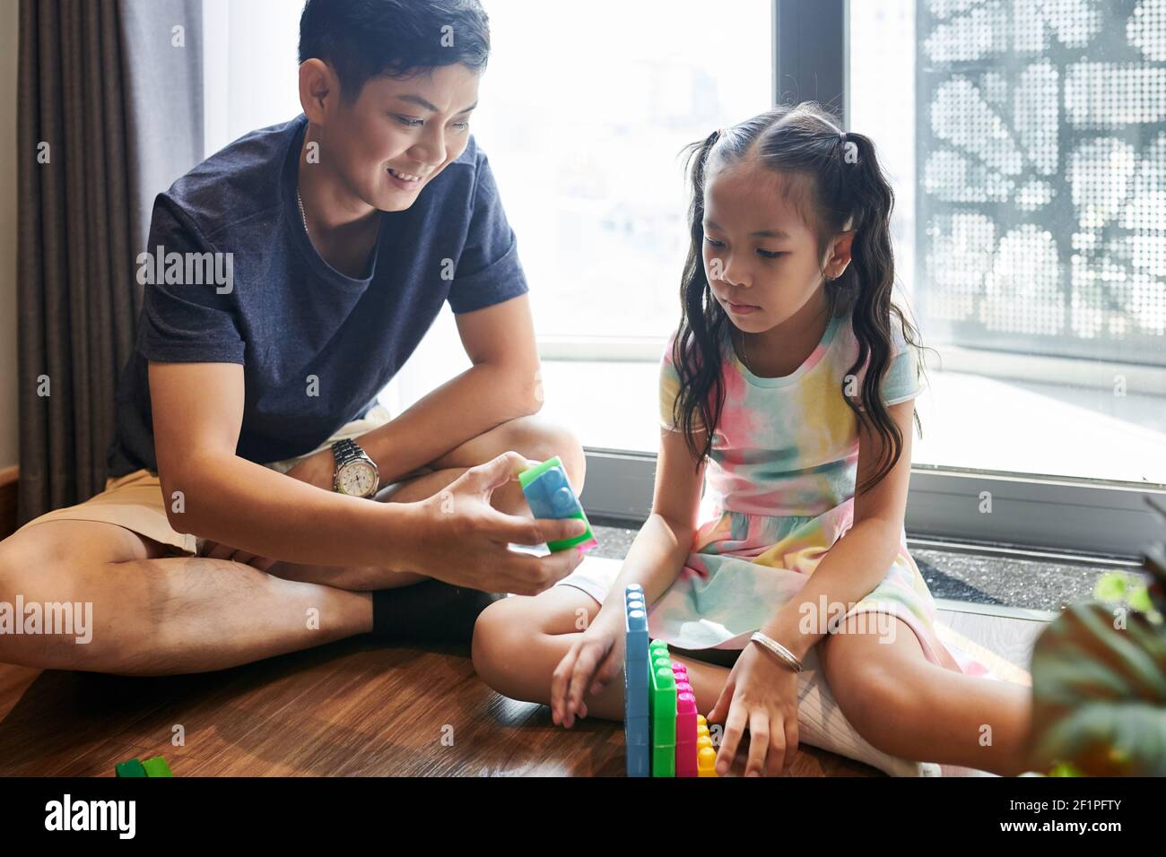 Padre e figlia trascorrono il tempo insieme e costruiscono passi con blocchi in plastica Foto Stock