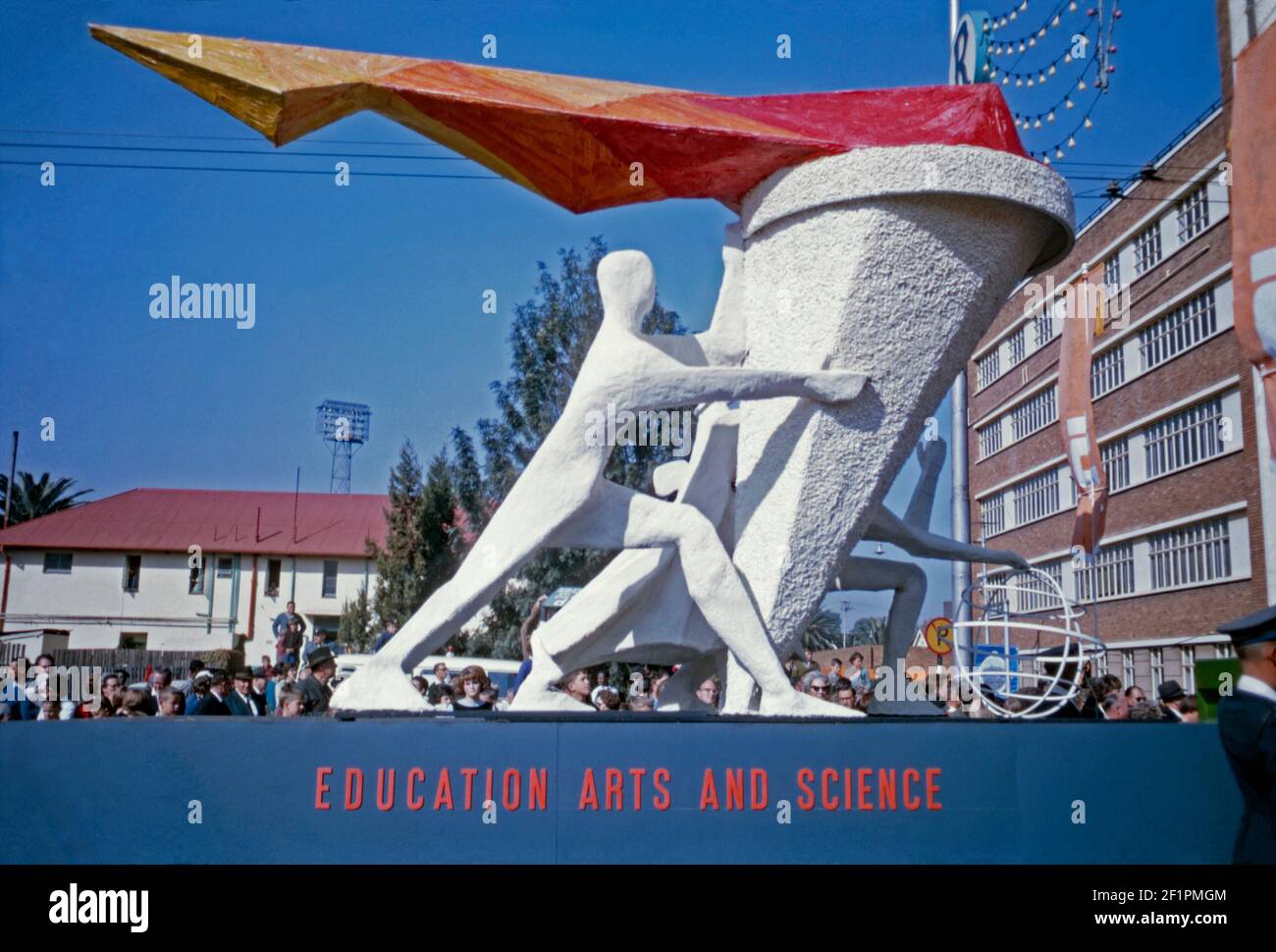 Parata galleggiante promuovere l'istruzione, le arti e la scienza, durante l'era dell'apartheid, Durban, Sudafrica, 1966. Il galleggiante presenta una ‘sscultura’ moderna di una figura che regge una torcia con fiamme che si innalzano da essa. Si tratta di un pubblico bianco che guarda questo evento. Questa immagine proviene da un vecchio lucido a colori Kodak dilettante da 35 mm. Foto Stock
