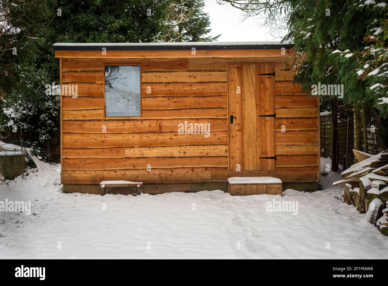 Waney bordo boscoso giardino capannone coperto di neve dopo pesante nevicata Foto Stock