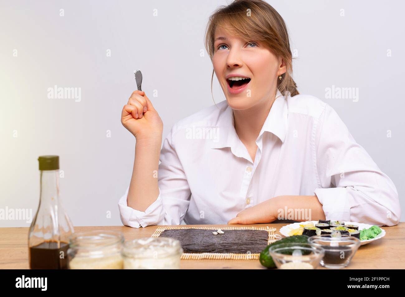 La giovane donna caucasica fa sushi a casa, prendendo online corsi di cucina, flusso di cibo blogging, internet. Piatti asiatici giapponesi fatti in casa Foto Stock