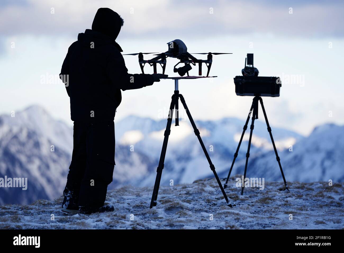 Silhouette di pilota drone con attrezzatura in cima alla montagna in inverno Foto Stock
