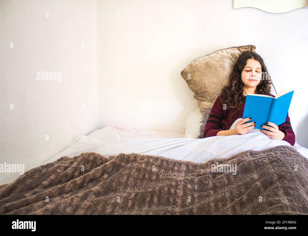 giovane donna sdraiata nel letto di lettura Foto Stock