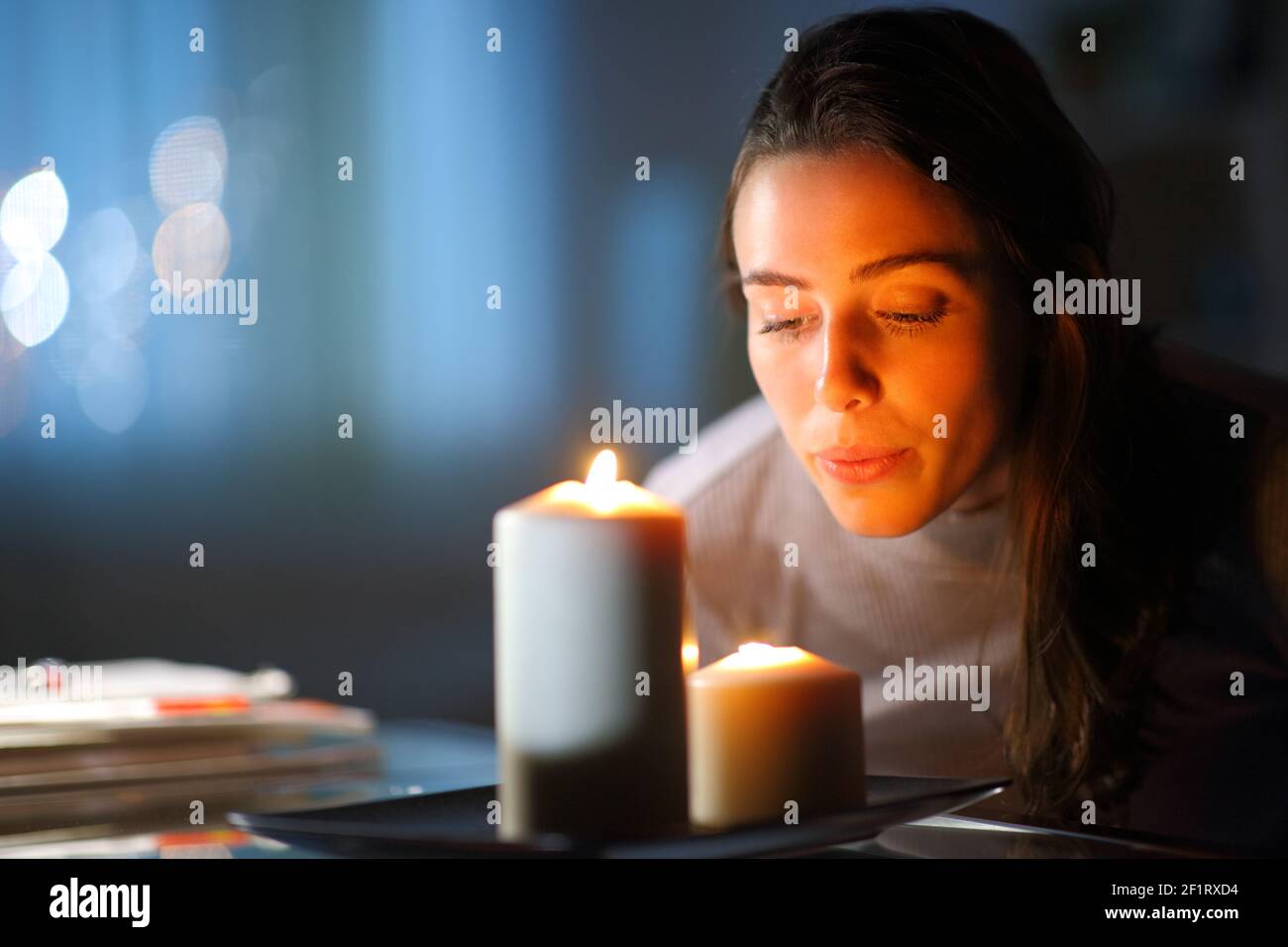 Bella donna che soffia fuori candele nel soggiorno a. casa di notte Foto Stock