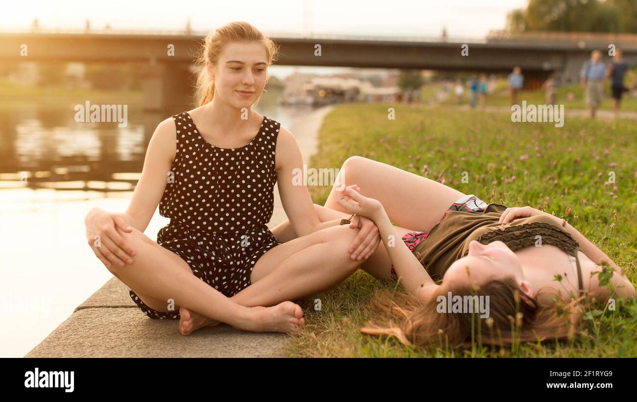 Due ragazze giovani sull'argine di pietra. Bella luce soffusa al tramonto. Foto Stock