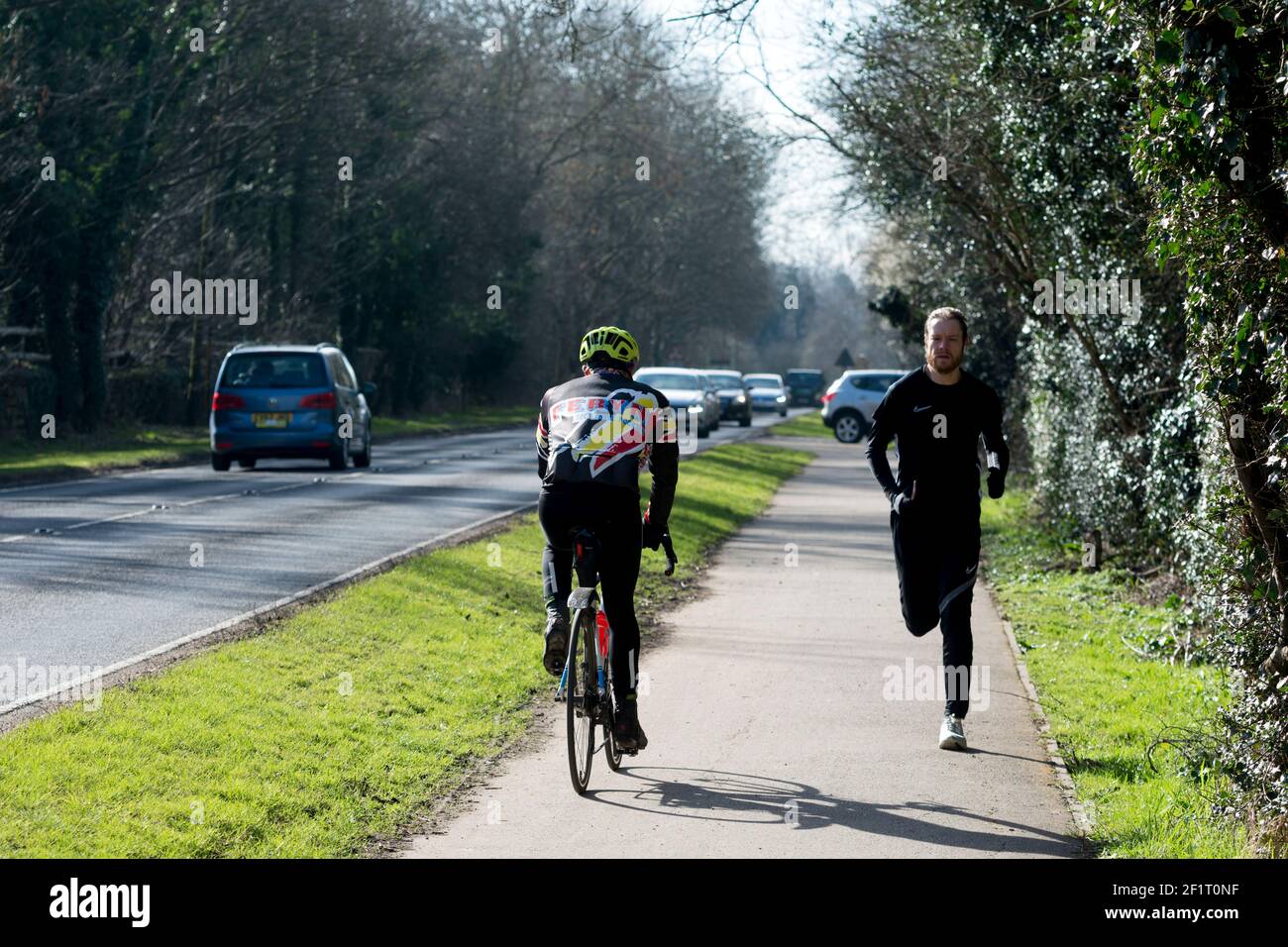 Un ciclista e corridore su un doppio percorso ciclistico/pedonale durante il Lockdown Covid-19, Warwick, Regno Unito. Marzo 2021. Foto Stock