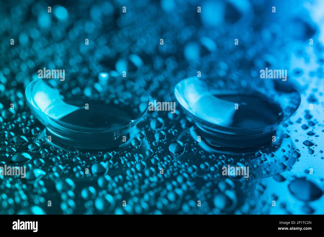 Lenti a contatto, su sfondo verde-blu. Due lenti a contatto con gocce su sfondo verde-blu. Foto Stock