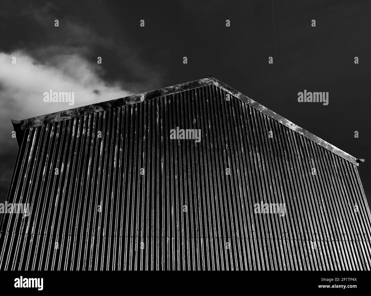 Un fienile nero in metallo corrugato contro un cielo nero. In bianco e nero. North Pennines, Contea di Durham, Inghilterra Foto Stock