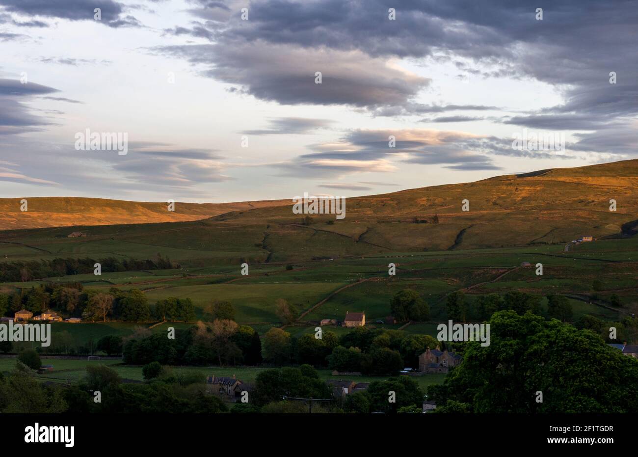 Una vista delle colline del Pennino Nord, che mostra il villaggio di St John's Chapel, Weardale, County Durham, Regno Unito in serata, sole di primavera Foto Stock