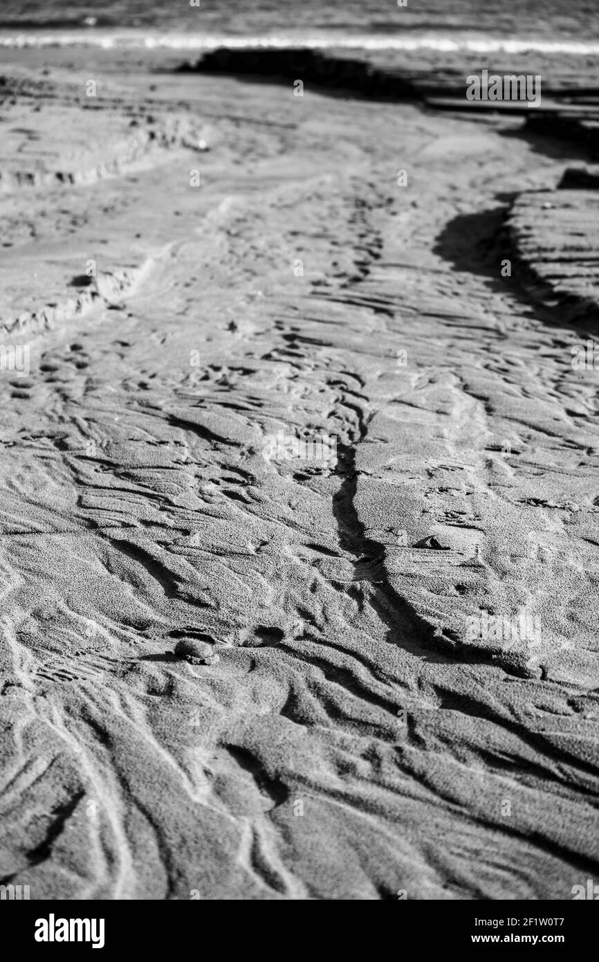 Textures sulla sabbia della spiaggia dopo la tempesta in un giorno di sole d'inverno Foto Stock