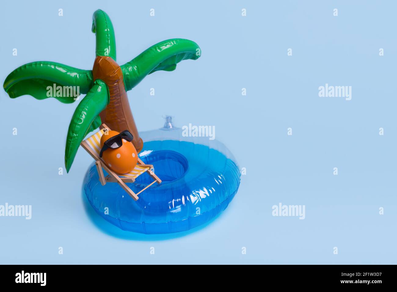 Composizione creativa divertente con uovo di Pasqua con occhiali da sole mentre si siede sulla sedia a sdraio su palme gonfiabili. Trendy vacanza estiva minima, vacanze estive Foto Stock
