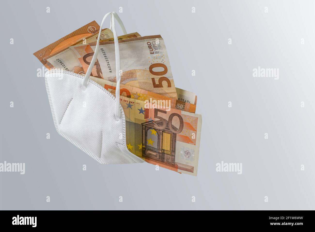 Maschera medica ffp2 contro il virus covid-19 riempito di banconote in euro, concetto di arricchimento per corruzione o aumento dei costi dell'assistenza sanitaria a pande Foto Stock