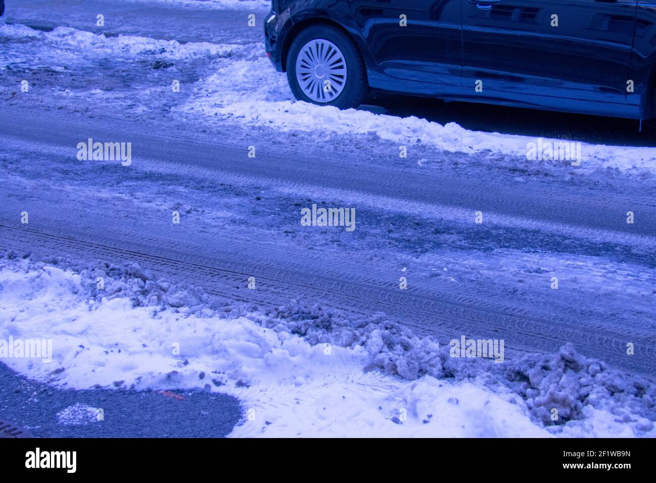 Cingoli pneumatici in neve e ghiaccio su strada non sottoposta a manutenzione A Berlino Foto Stock